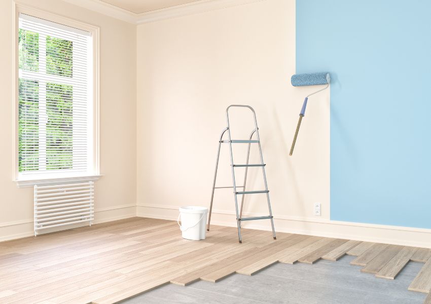 a lander and paint roller in a white room with the roller painting the walls blue