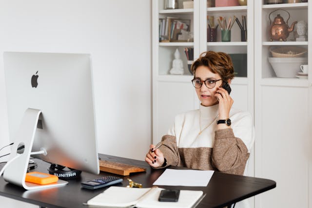 A property manager speaking on the phone while looking at the computer